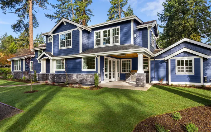 Back patio of a house with navy blue siding and stone veneer base.